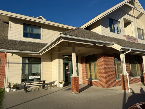 Exterior of office building, green doors, picnic table, brick walls