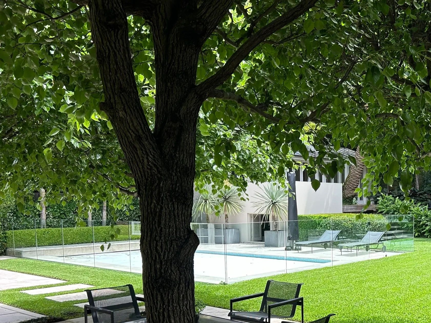 Outdoor seating area by a pool surrounded by lawns in Sydney.