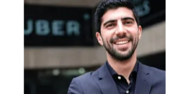 Smiling man in a suit standing outside an Uber office.