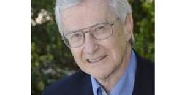 Elderly man with glasses smiling outdoors.