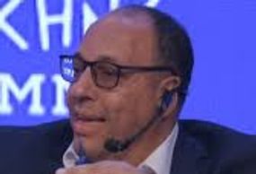 Man wearing glasses and a headset speaking on stage.