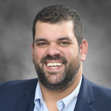 Smiling man in a suit jacket and dress shirt.