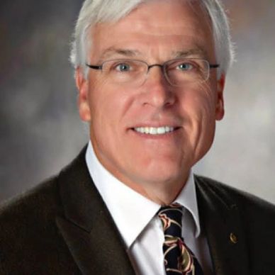 Portrait of an older man in glasses and a suit.