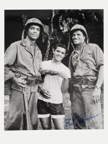Two soldiers and a young man smiling for a photo.