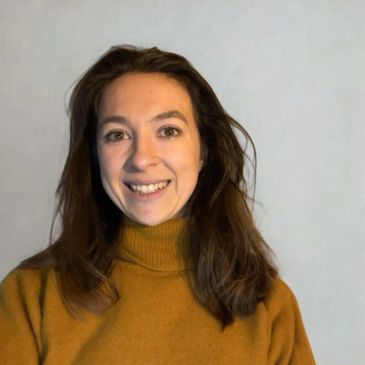 Smiling woman in a mustard yellow turtleneck sweater.