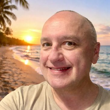 Smiling man on a beach at sunset.