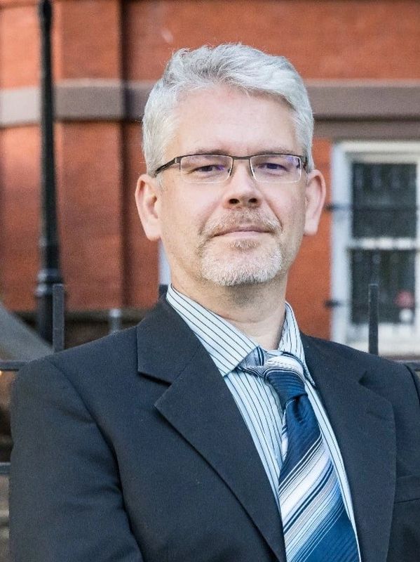 Confident middle-aged man in suit and glasses.