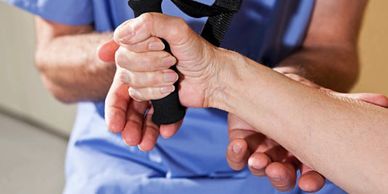 Therapist assisting patient with hand exercise using a strap.