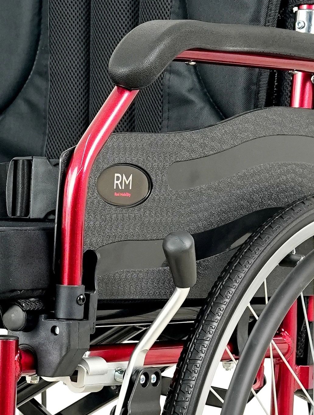 Close-up of a red and black wheelchair with visible branding and wheel details.