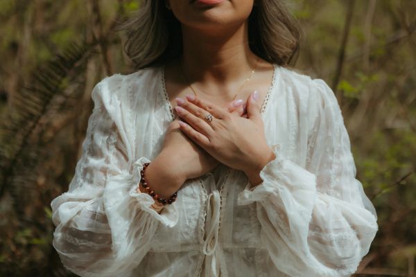 Person wearing white blouse with hands crossed over chest.