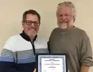 Two men smiling, holding a certificate.