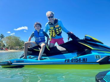 Two people with life jackets on a Yamaha jet ski on calm water.