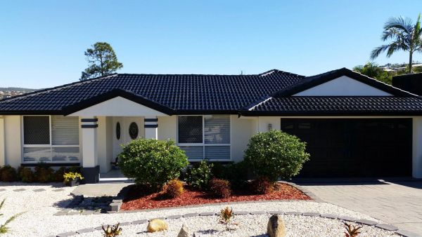 Modern suburban house with a dark roof and landscaped front yard.