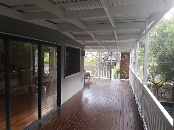 Covered wooden porch with railing and sliding glass door.