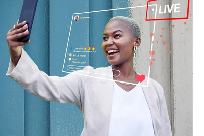 Female influencer is smiling at her smart phone and taking a video selfie 
