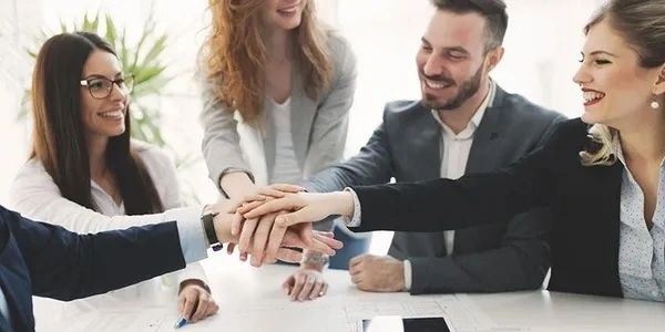 A team of professionals stacking hands in a gesture of unity and collaboration.
