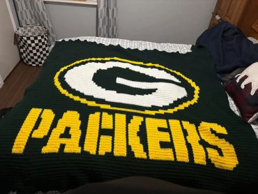 Green Bay Packers crochet blanket on a bed.