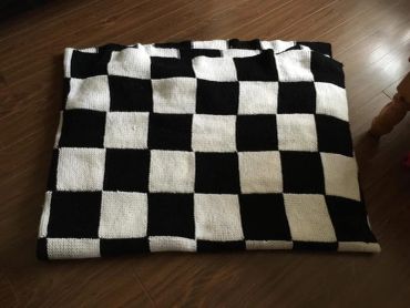 Folded black and white checkered blanket on wooden floor.