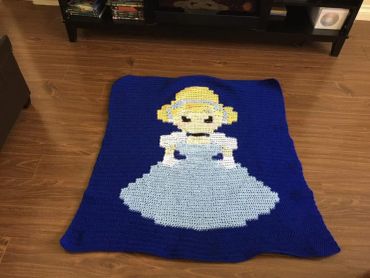 Crocheted blanket featuring a girl in a blue dress.