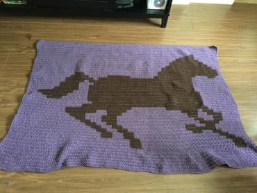 Purple blanket with a brown horse design.
