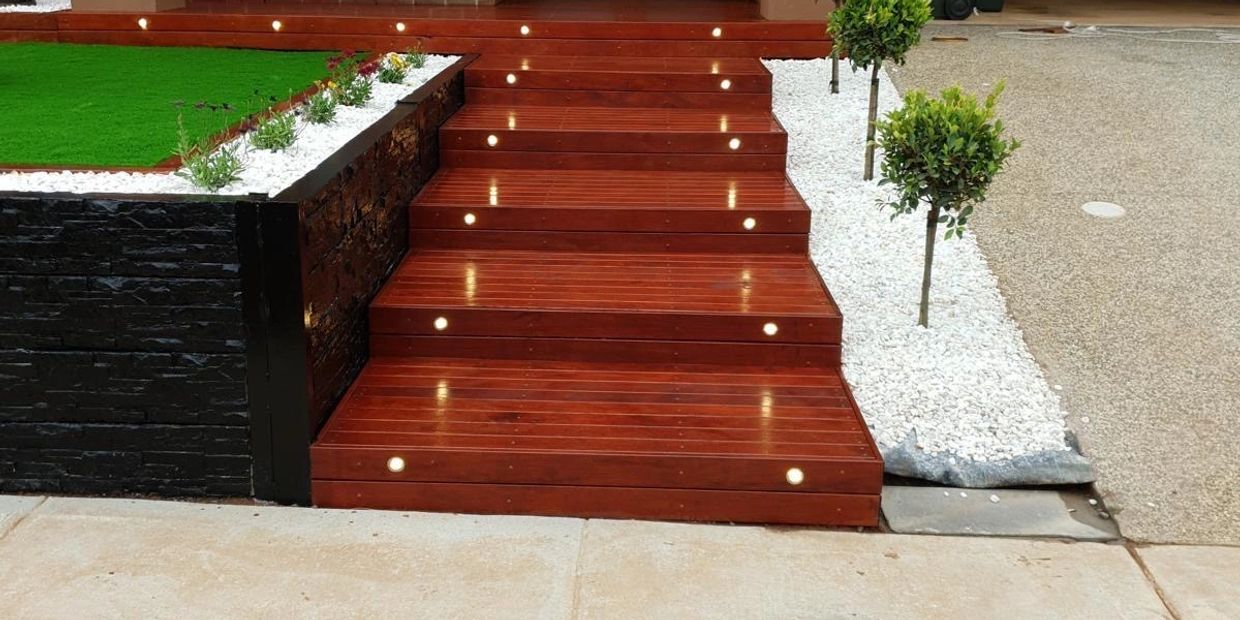 Modern wooden steps with embedded lights leading to a front door.