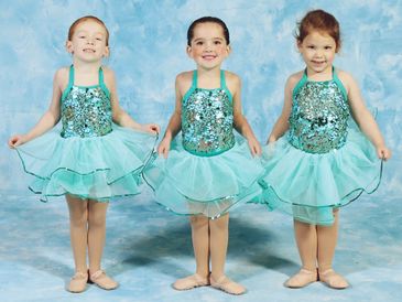 Three young girls in aqua blue ballet costumes.