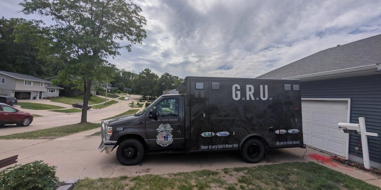 A black G.R.U. emergency response vehicle parked in a residential driveway.