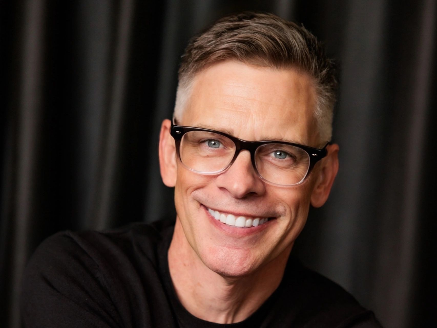 Smiling man with glasses and short hair.