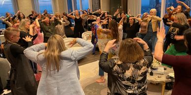 Group of people doing a synchronized dance indoors at sunset.