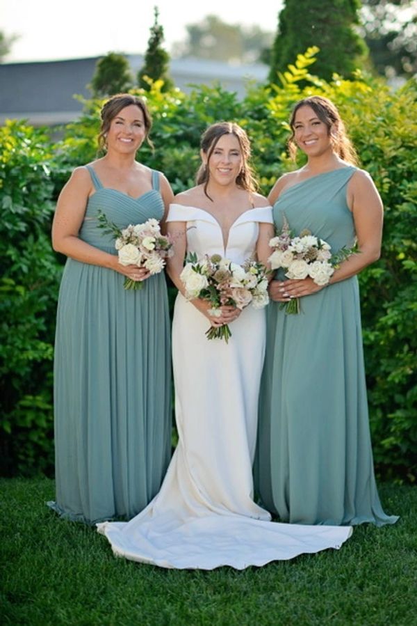 Three women standing in a garden holding a bunch of white flowers