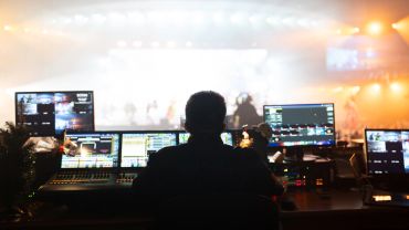 Person operating lighting and sound controls at event.