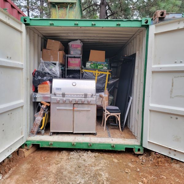 Storage container filled with household items including a grill and chairs.