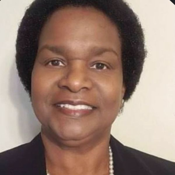 Professional portrait of a smiling woman with short natural hair.