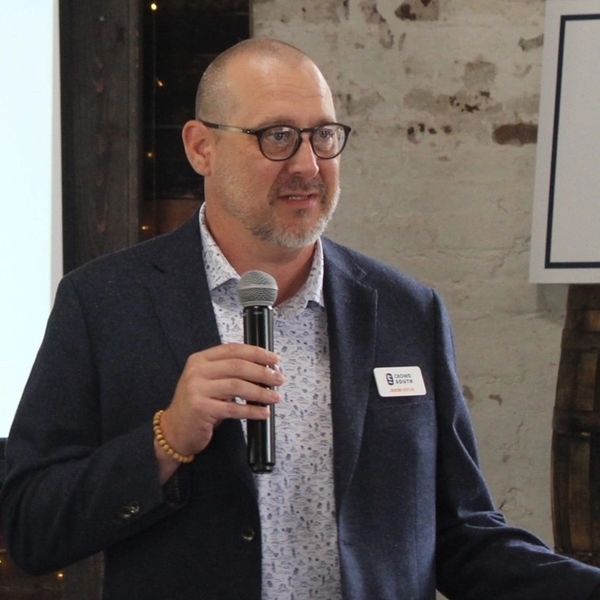 Man speaking into a microphone at an indoor event.