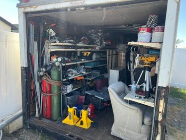 A cluttered workshop inside a trailer with tools and equipment.