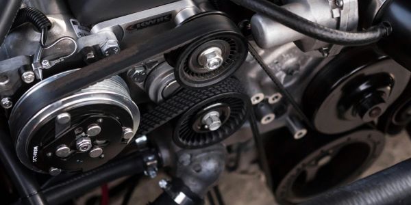 Close-up of an engines belt and pulley system.