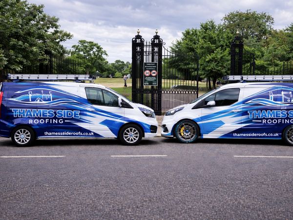 Two Thames Side Roofing vans parked facing each other with blue and white designs.