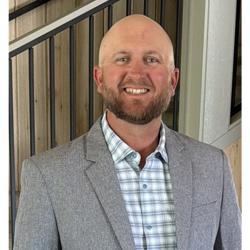 Smiling bald man in a gray blazer and checkered shirt.