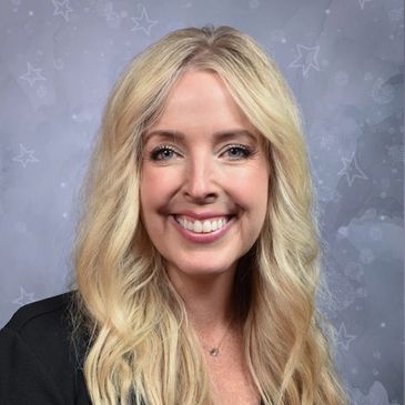 Smiling blonde woman with wavy hair and a starry background.