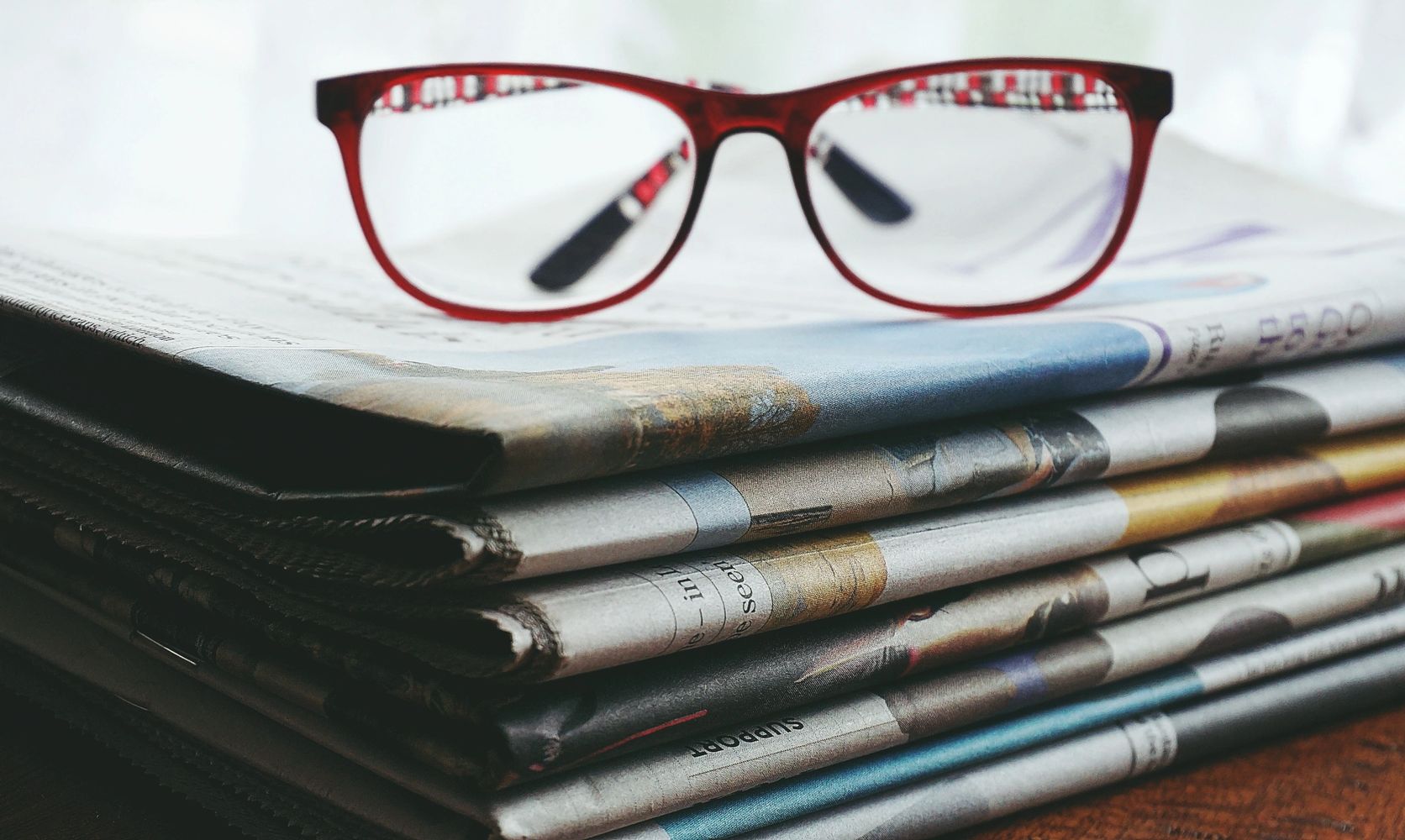 Smart eye glasses and a stack of newspapers that express the smart comms  you get from Kathy King