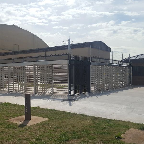 Turnstile security gates outside a military base building under a cloudy sky.