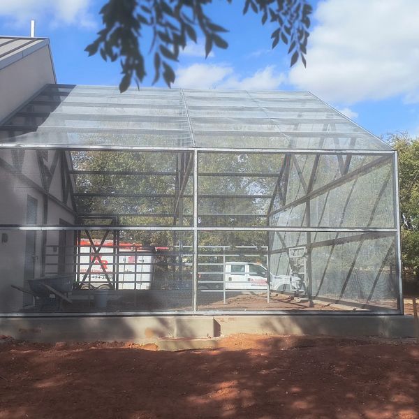 Large metal mesh enclosure attached to a building under a blue sky.