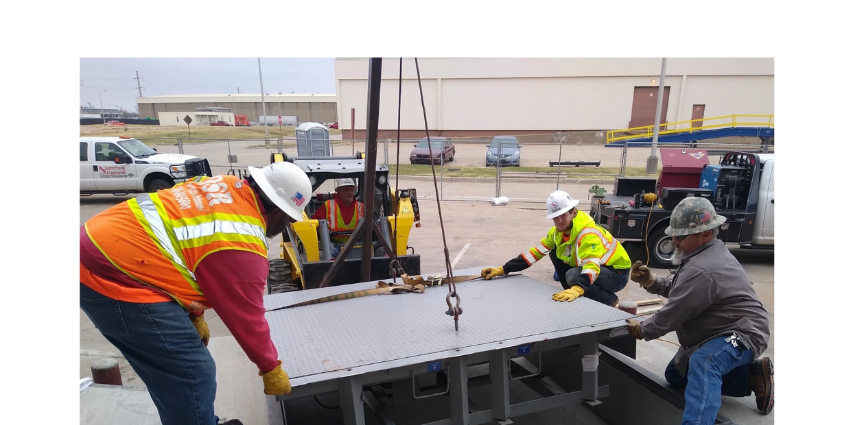 Construction workers installing a heavy metal platform over a pit.