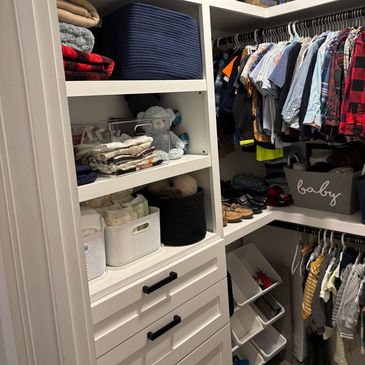Organized walk-in closet with clothes, storage bins, and shelves.