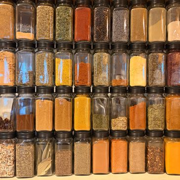 Organized jars of various colorful spices on a shelf.