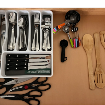 Organized kitchen drawer with cutlery, measuring spoons, and wooden utensils.