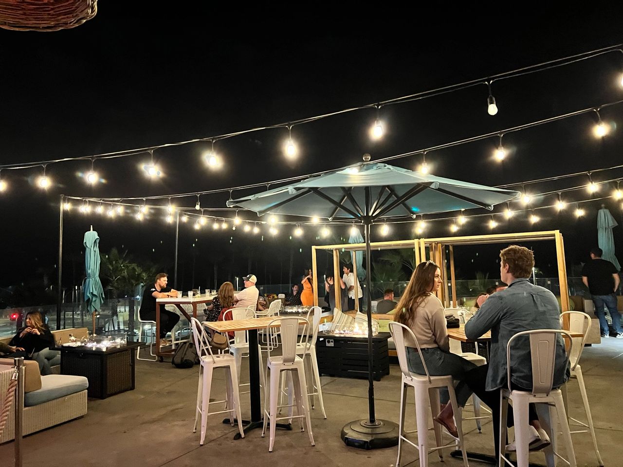A nighttime view of the patio with tall tables and couches
