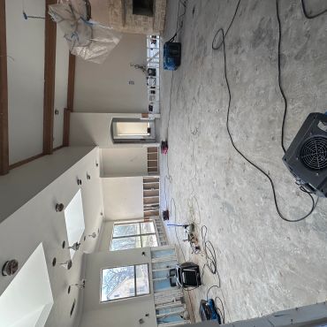 Large room under renovation with exposed walls and construction equipment.