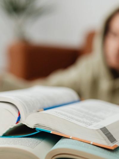 Open books with a person blurred in the background.