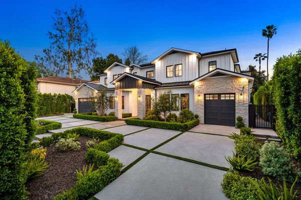 Luxurious modern farmhouse with manicured landscaping at twilight.